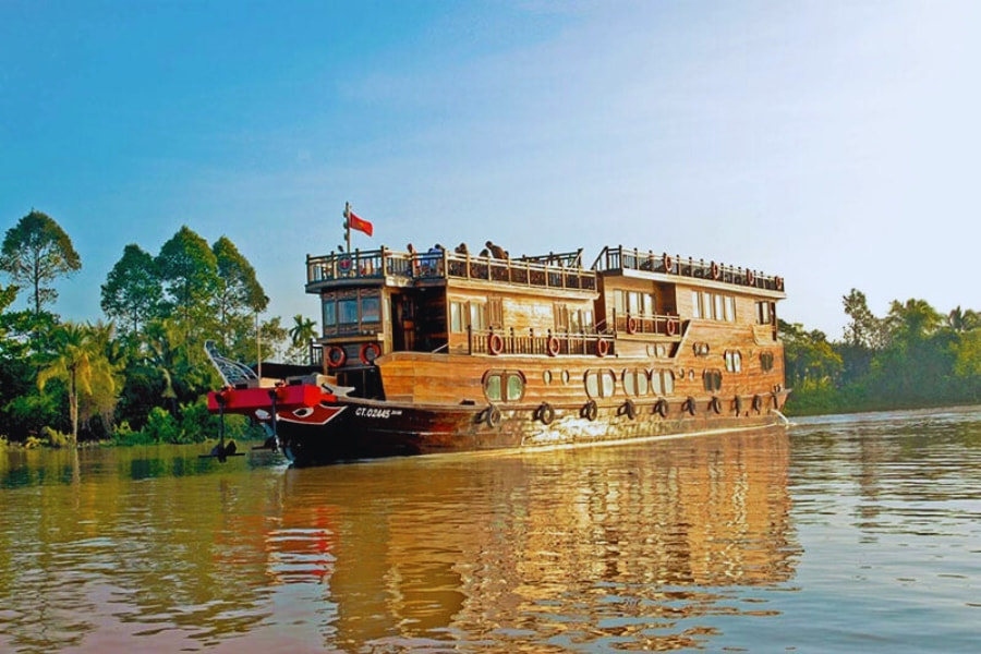 Traditional wooden Mekong River Cruise boat cruising through calm waters by Auasia Travel